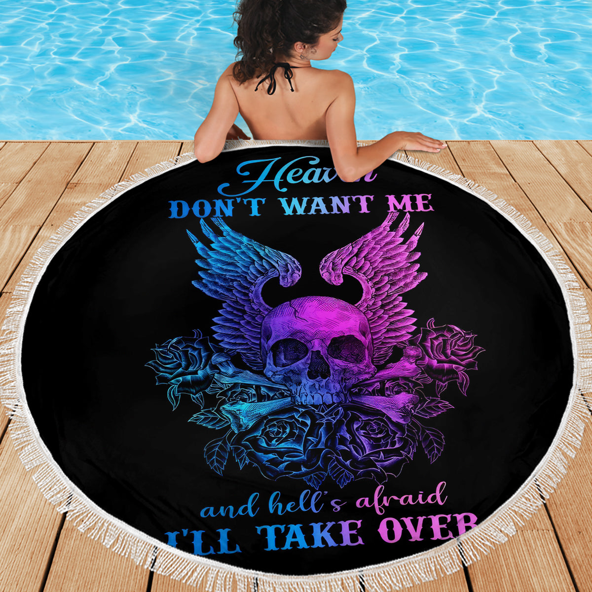 Black round beach blanket with skull-wings graphic and slogan text, fringed edge