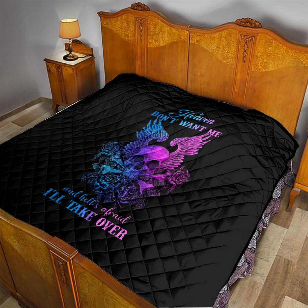 Black quilt blanket with diamond quilting and purple/blue winged skull graphic on bed