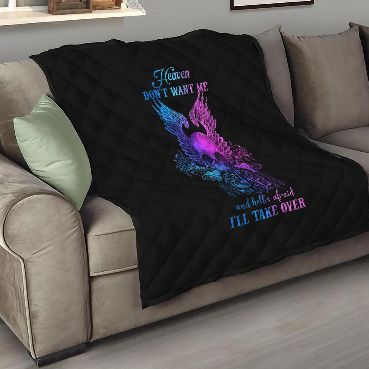 Black quilt blanket with diamond quilting and purple/blue winged skull graphic on sofa