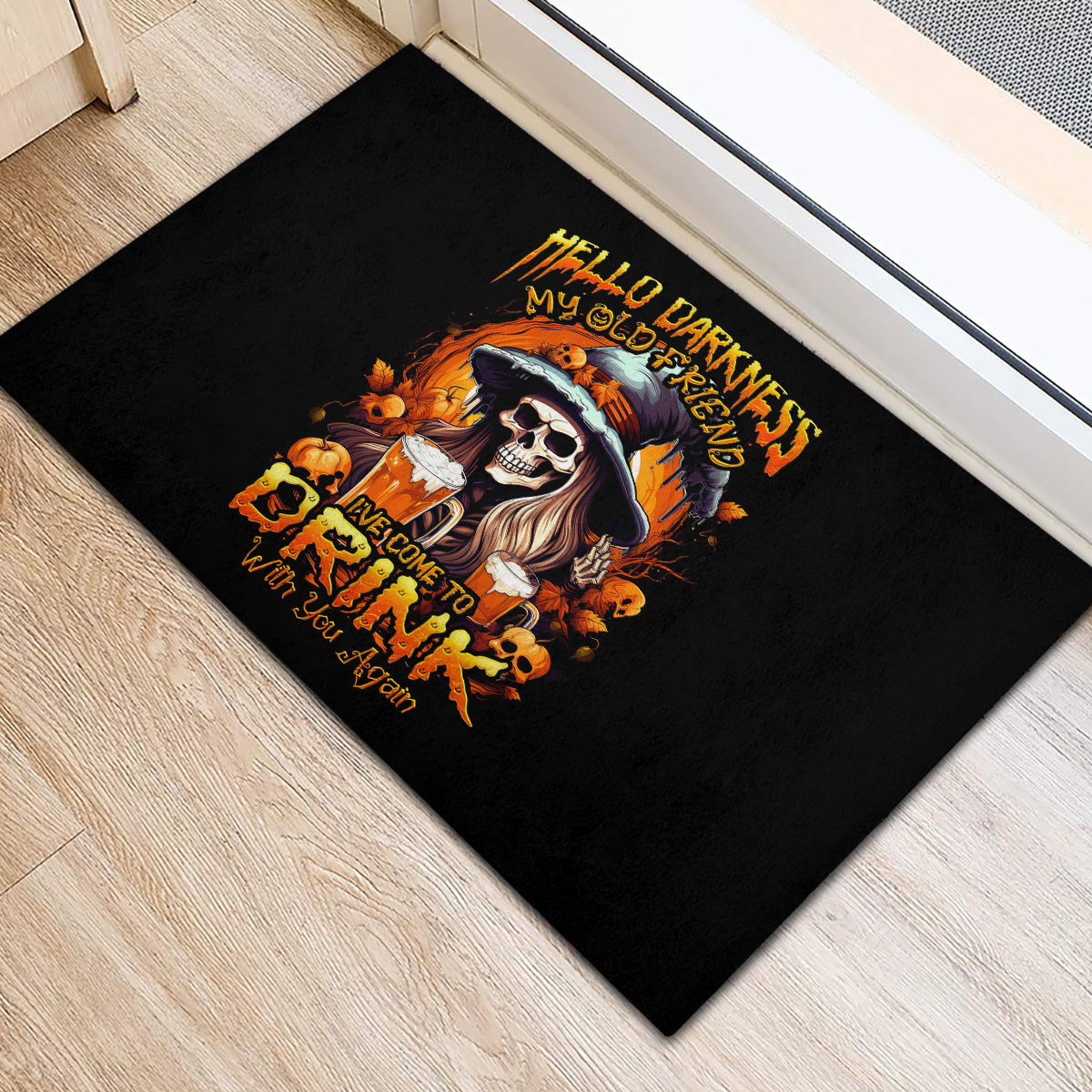 Black rubber doormat with witch skull design and orange Halloween lettering