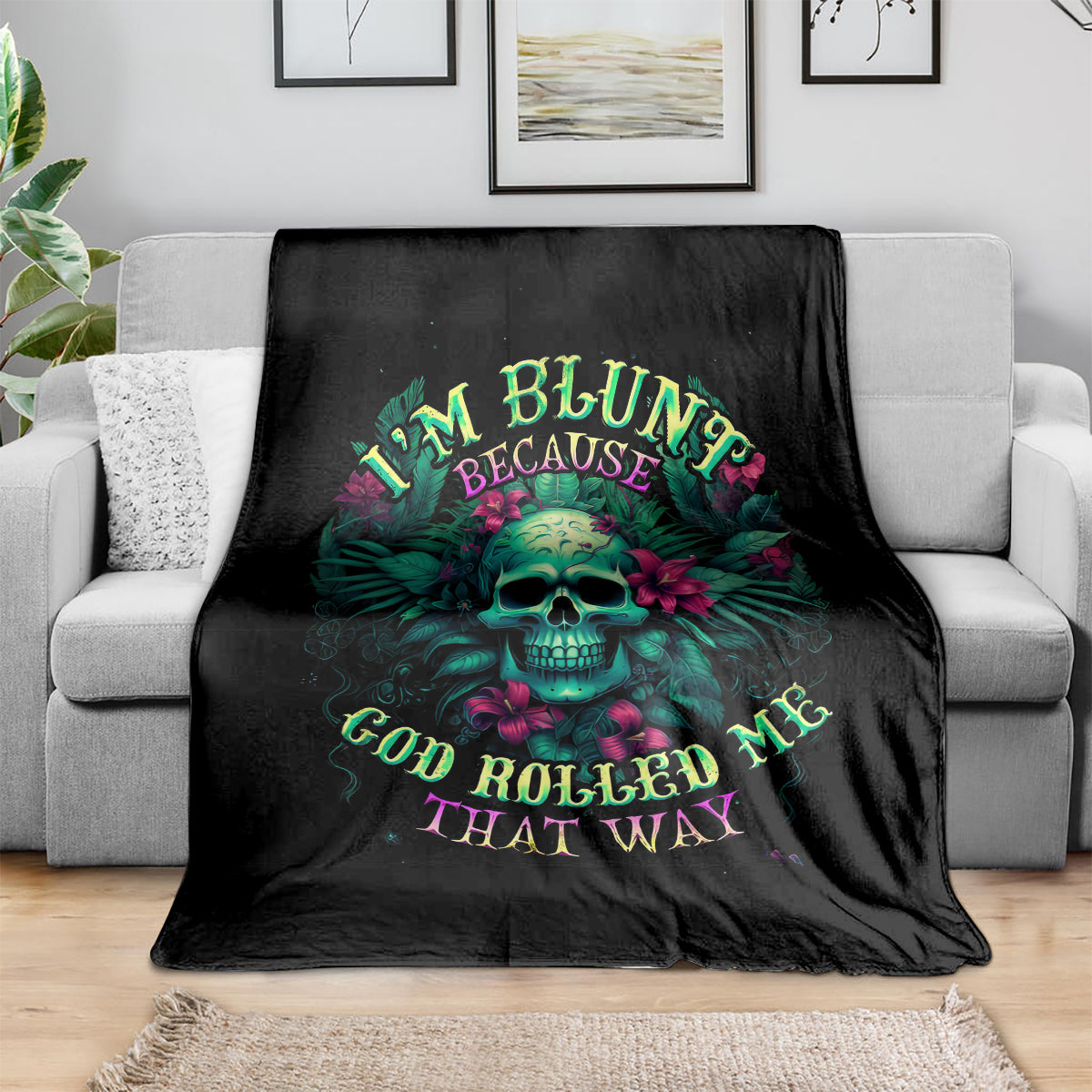 Black skull graphic throw blanket with colorful text design, draped over a sofa