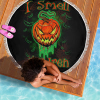 Round black beach blanket with fringed edge, jack-o'-lantern skull and green text graphic