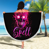 Black round beach blanket with fringed edge, purple skull 'Spell' design, held on sand.