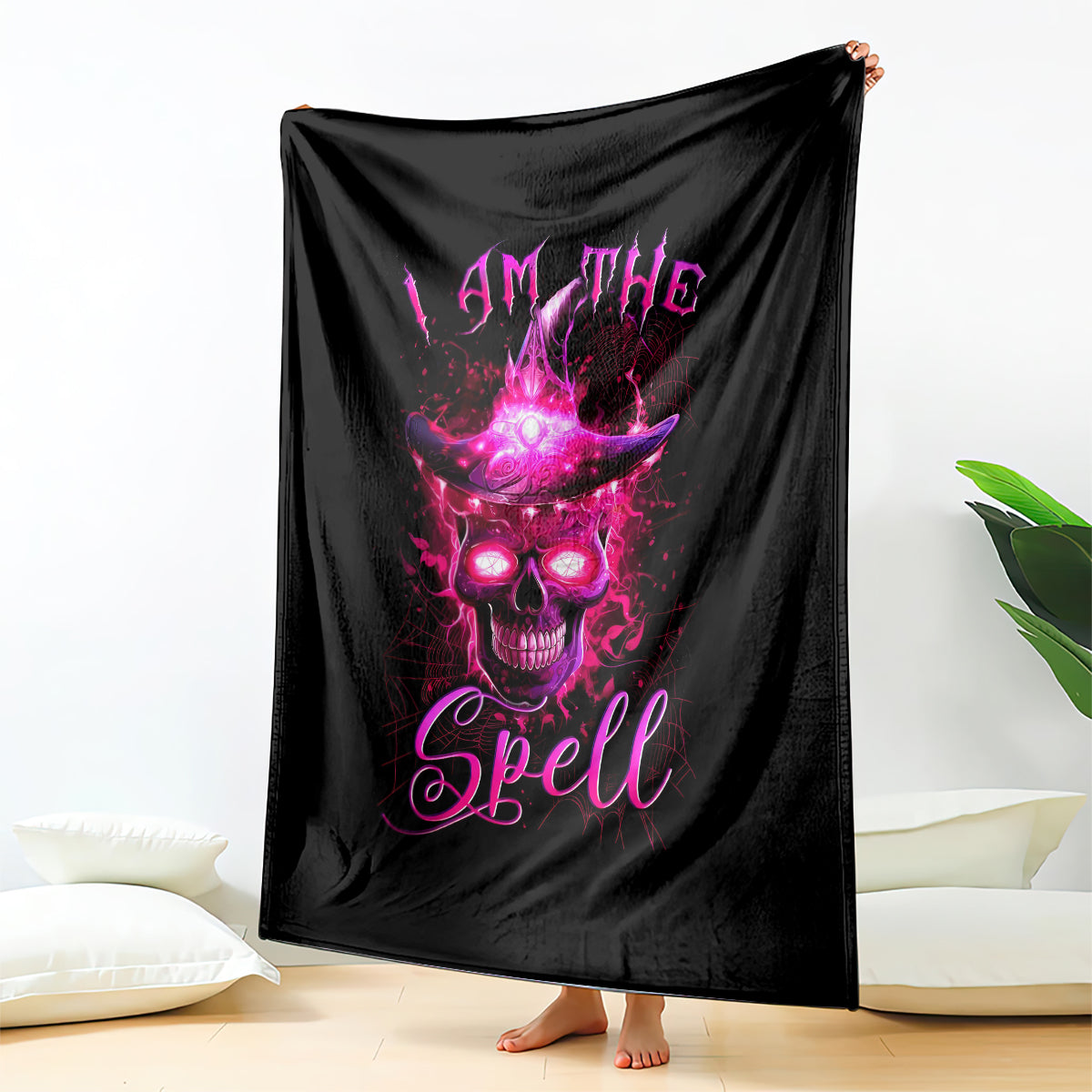 Black 'I AM THE Spell' witch skull blanket hanging on wall with purple glow