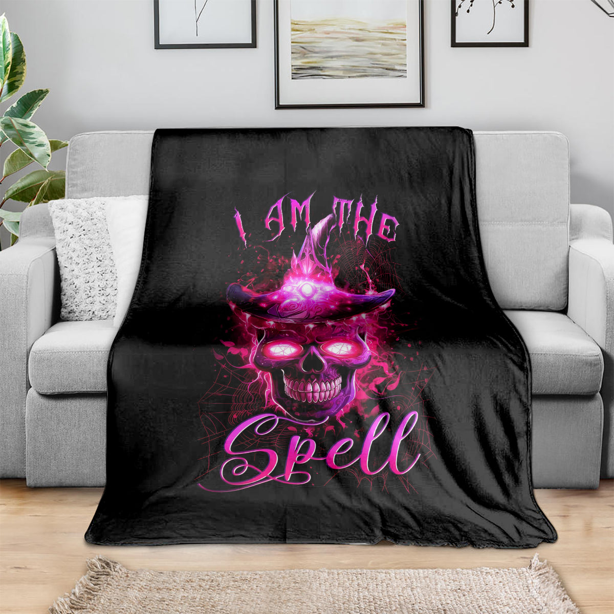 Black witch skull blanket with purple 'I AM THE Spell' graphic on draped couch