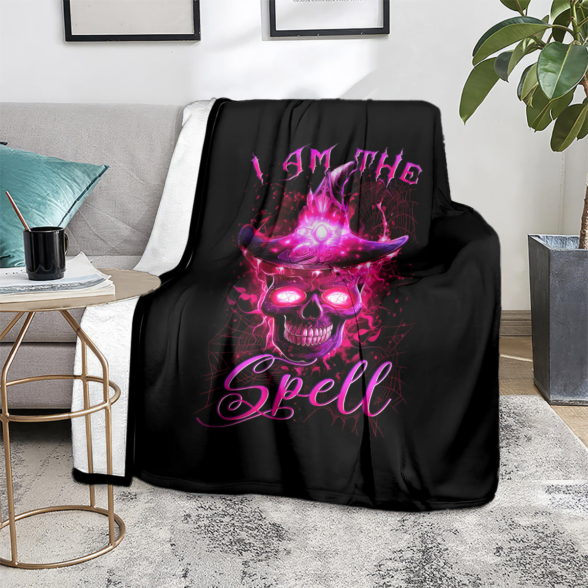 Black witch skull blanket with purple 'I AM THE Spell' design, laid on couch