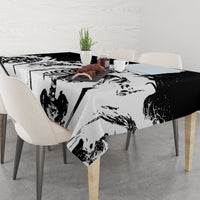 White tablecloth on dining table, black-and-gray skull face and ribcage print across.