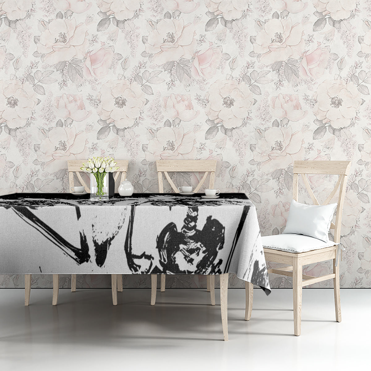 White tablecloth on dining table, black-and-gray skull face print with subtle rose detail.
