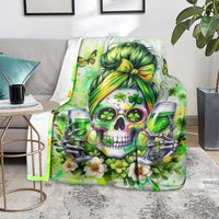 Green skull blanket on a couch chair, showing wine glasses, clovers, and blossoms