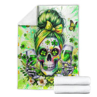 Green skull blanket featuring a green-haired bow, folded with towels beside it