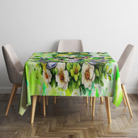 Green tablecloth with large flower print and leafy pattern, laid on dining table