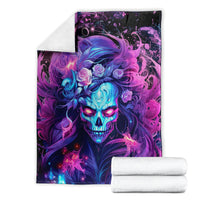 Skull graphic blanket with purple-blue neon artwork, shown with folded white towels