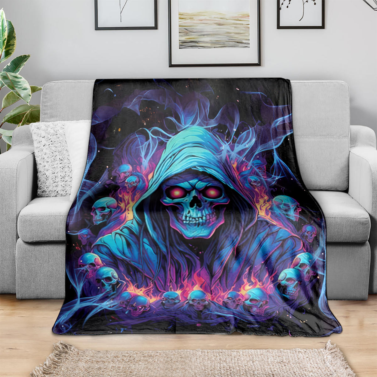 Skull art blanket draped over gray sofa, blue hooded grim reaper face design