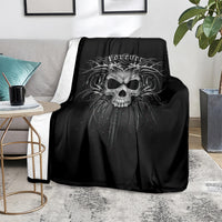 Black skull print blanket folded and spread on a gray sofa