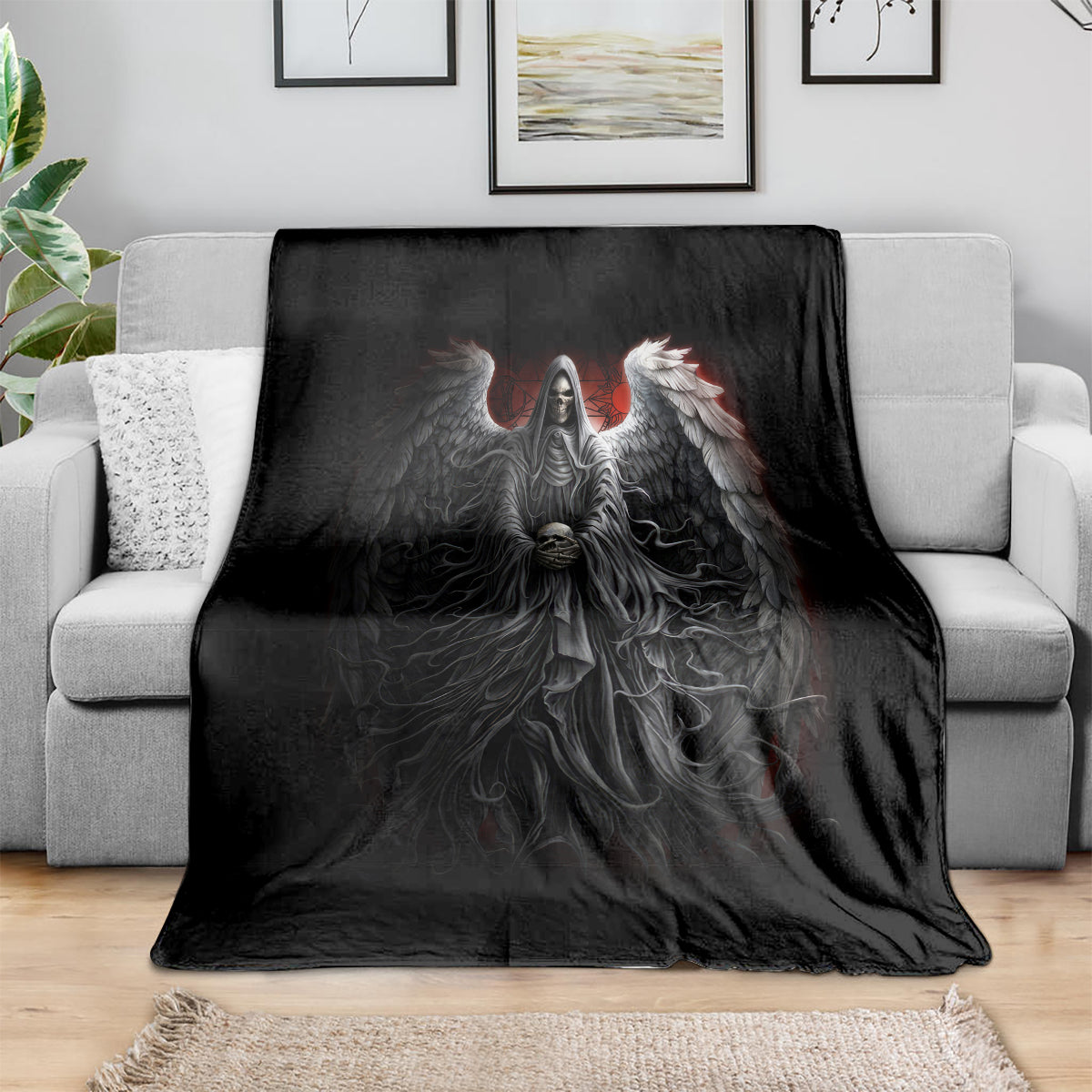 Black skull and angel wing graphic throw blanket spread across a light sofa