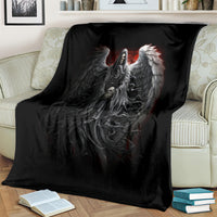 Black angel wings and skull graphic throw blanket covering a sofa with books nearby