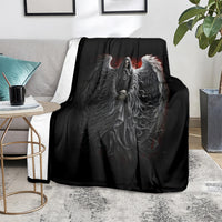 Black skull and angel wing graphic throw blanket on a living room floor