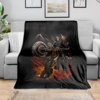 Black death-angel motorcycle blanket with flaming skull print, spread on gray sofa