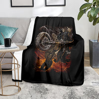 Black death-angel motorcycle blanket with flaming skull graphic, folded on living room sofa