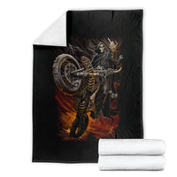 Black death-angel motorcycle blanket with flaming skull print, folded beside white towels