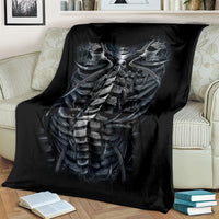 Black skeleton torso blanket with skull and ribcage graphic, draped on couch