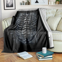Black skeleton skull and spine blanket, spread across couch with visible print detail