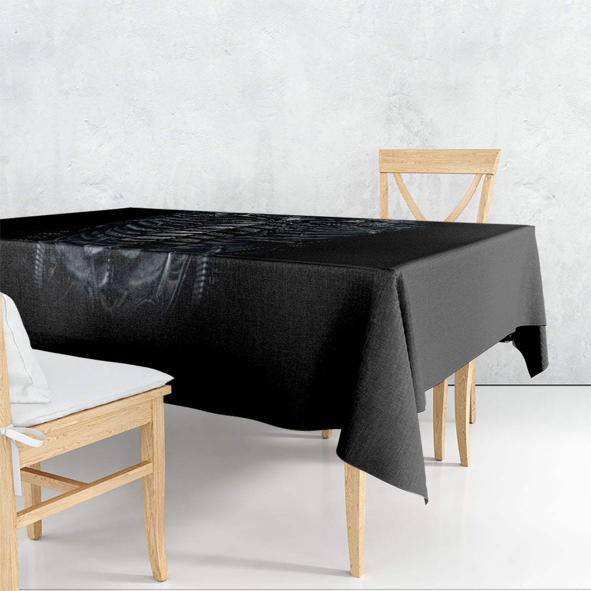 Black skeleton tablecloth draped over dining table, glossy print with skull and ribcage design.