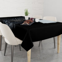 Black skeleton skull tablecloth spread across dining table, centered artwork with floral accents.