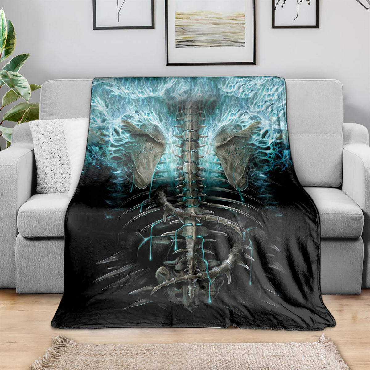 Black skeleton blanket with teal-blue skull and ribcage artwork, draped on a sofa