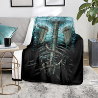 Black skull and skeleton blanket with teal-blue glowing anatomy art, folded on floor