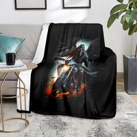 Black fantasy blanket with glowing-eyed skull rider artwork, over a gray armchair
