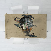 Beige rectangular tablecloth with dark skull and floral bird graphic in the center