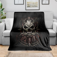 Black blanket with mechanical skull artwork draped over gray sofa