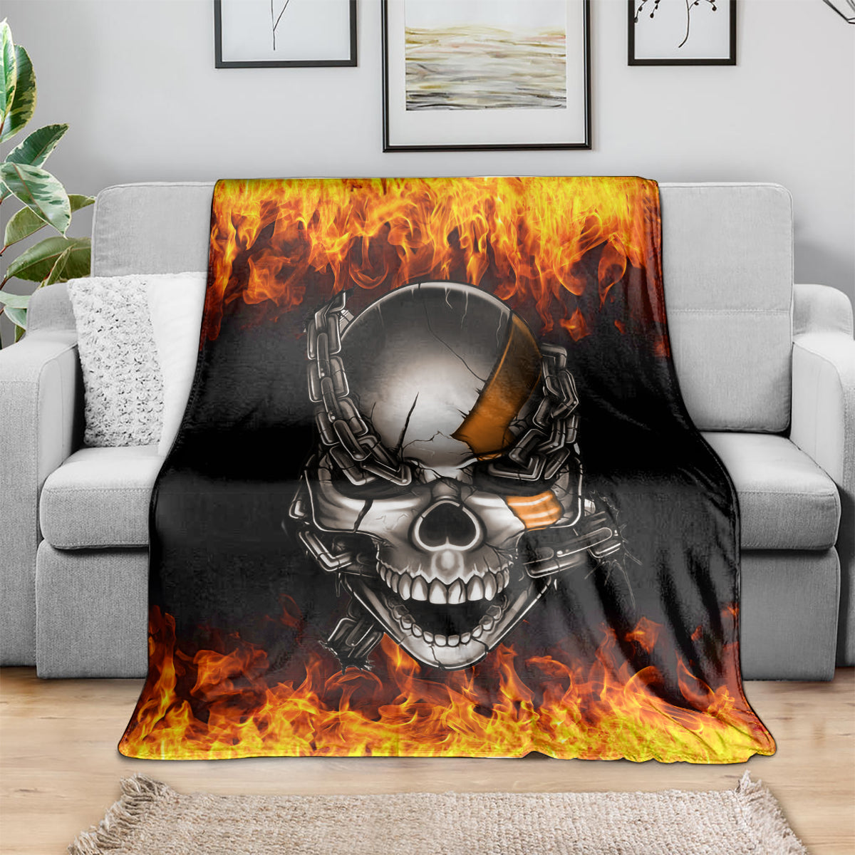 Black skull and chain blanket with fiery flames, draped over gray sofa