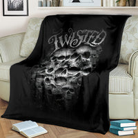 Black throw blanket with twisted head skull print, folded and draped over a couch