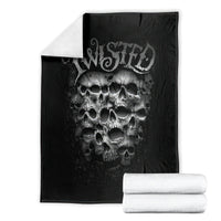 Black throw blanket with twisted head skull print, stacked with white rolled towels