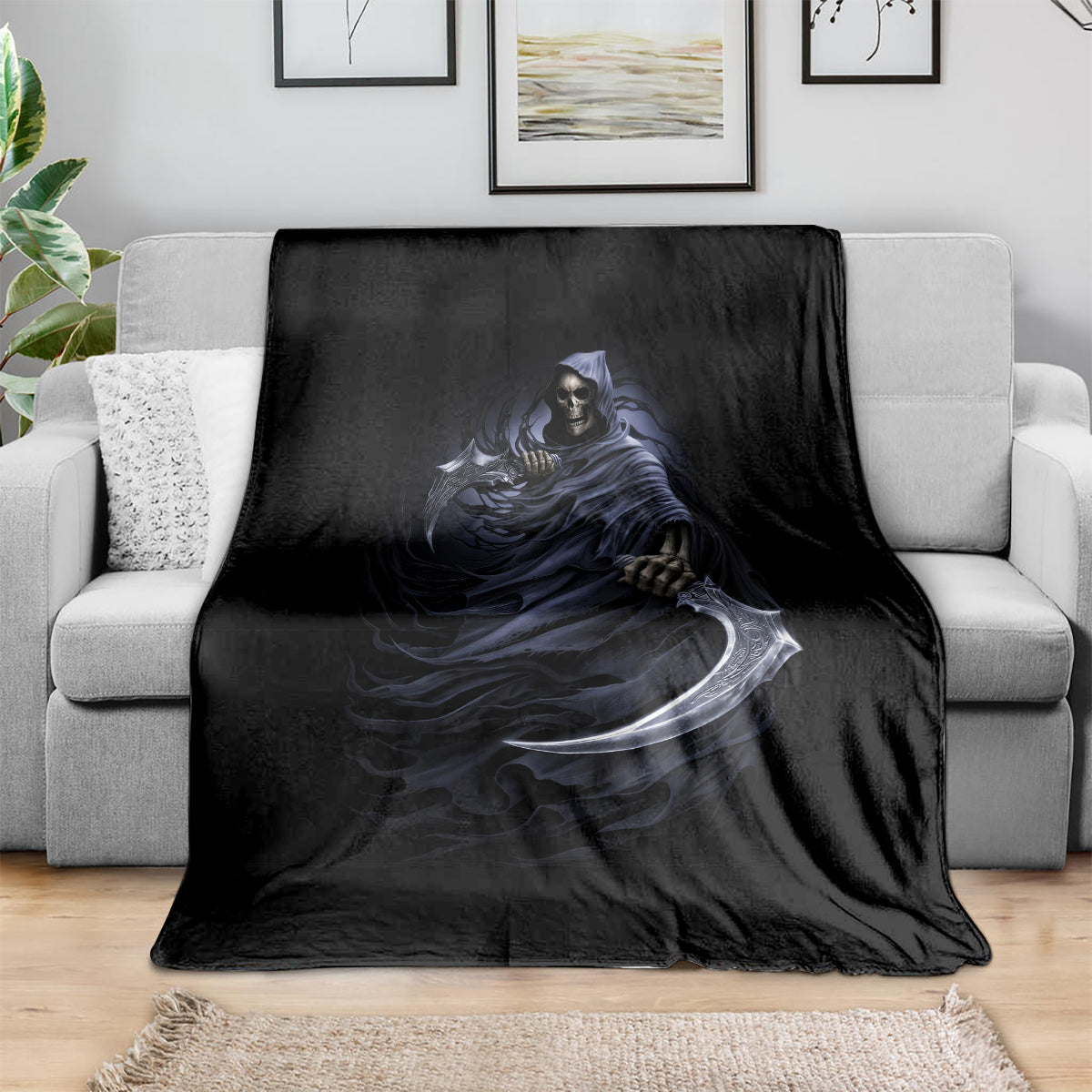 Black blanket draped over light gray sofa, featuring blue grim reaper skeleton and scythe