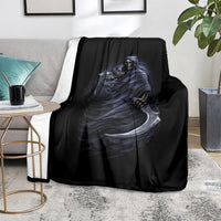 Black blanket over gray sofa with blue grim reaper skeleton skull and scythe print