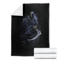 Black throw blanket with blue grim reaper skeleton skull graphic, folded with white towels