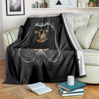 Black skull graphic blanket with hooded skull print, folded over striped sofa back