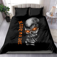 Black bedding set with large skull face print, orange vertical lettering, on-bed view with two shams