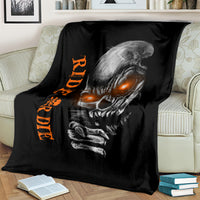 Black skull graphic blanket with orange lettering, draped across bed