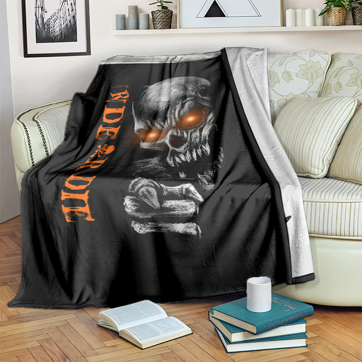 Black skull graphic blanket with orange text, draped over sofa with books
