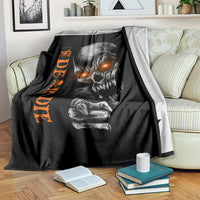 Black skull graphic blanket with orange text, draped over sofa with books