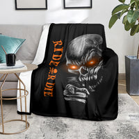 Black skull graphic blanket with orange lettering, laid on light rug