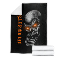 Black skull graphic blanket with orange lettering, folded with white towels