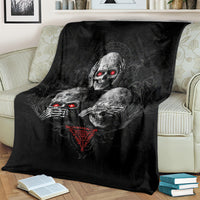 Black skull graphic throw blanket with red glowing eyes, draped over striped sofa cushions
