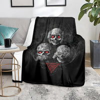 Black skull graphic throw blanket with three skeleton faces and red glowing eyes, draped