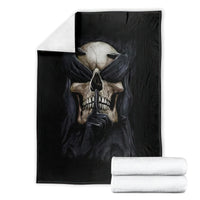 Black skull graphic blanket shown folded with stacks of white towels beside it