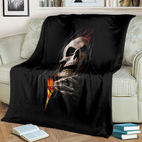 Black skull throw blanket draped on a sofa, featuring skeletal hands and flame design